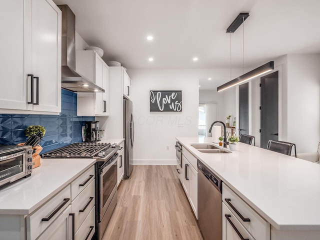 1210 Madison Ave, Columbus, OH 43205 - kitchen with stainless steel appliances, wall chimney range hood, light wood-type flooring, decorative backsplash, and an island with sink
