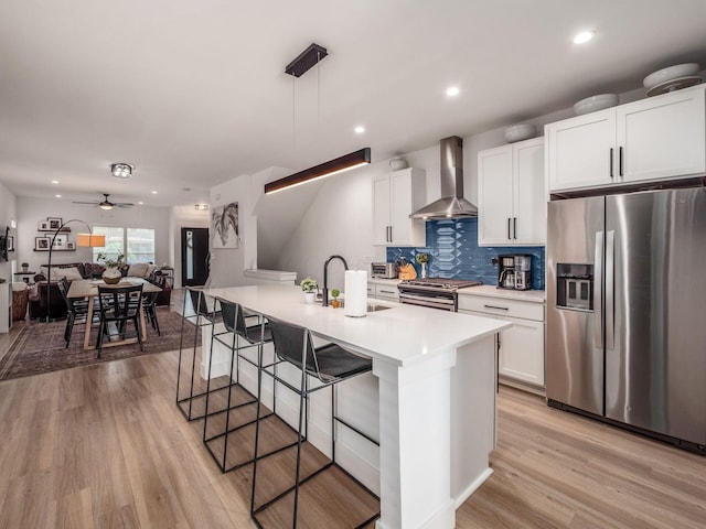 1210 Madison Ave, Columbus, OH 43205 - kitchen featuring appliances with stainless steel finishes, wall chimney range hood, a kitchen breakfast bar, light wood finished floors, and light countertops