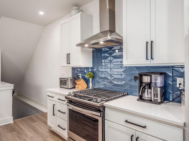 1210 Madison Ave, Columbus, OH 43205 - kitchen featuring wall chimney range hood, stainless steel gas range oven, light wood finished floors, white cabinets, and backsplash