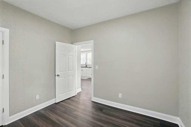 2718 Lagonda Ave, Springfield, OH 45503 - unfurnished room with dark wood-style floors, baseboards, a sink, and a textured wall