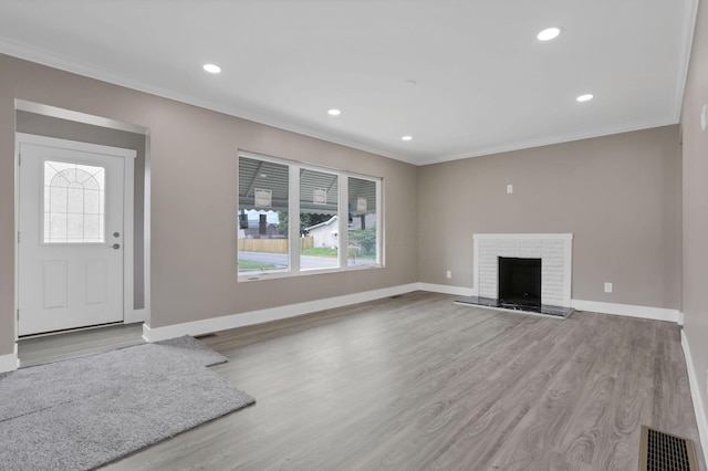 714 E 2nd St, Logan, OH 43138 - unfurnished living room featuring crown molding, wood finished floors, recessed lighting, and a brick fireplace