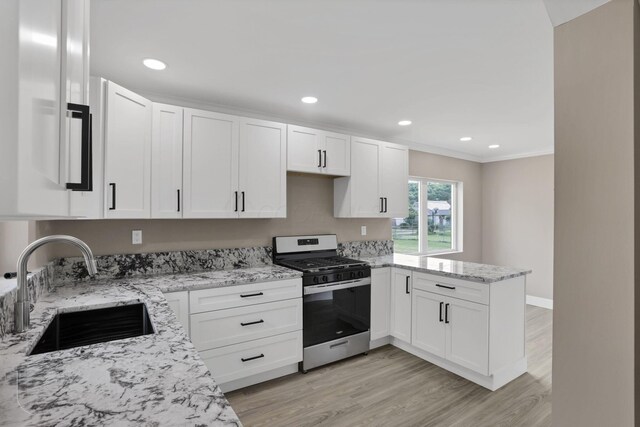 714 E 2nd St, Logan, OH 43138 - kitchen with stainless steel gas range, a peninsula, light stone countertops, white cabinetry, and light wood-type flooring
