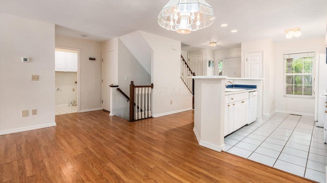 1486 Sedgefield Dr, New Albany, OH 43054 - kitchen featuring light wood-style flooring, white cabinetry, a chandelier, dishwasher, and light countertops