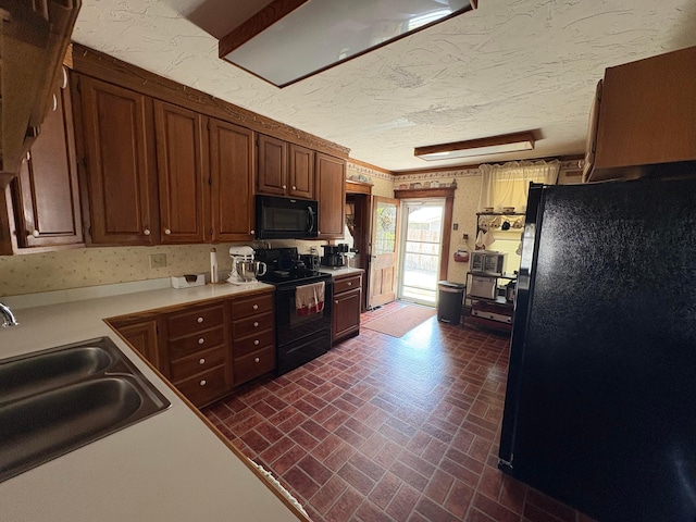 114 E N St, Mount Gilead, OH 43338 - kitchen featuring black appliances, brick patterned floors, light countertops, a textured ceiling, and brown cabinetry