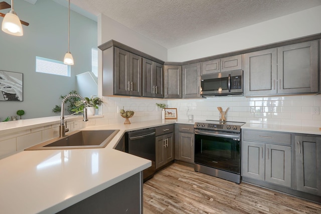 1957 Cumberland St, Newark, OH 43055 - kitchen featuring appliances with stainless steel finishes, light wood finished floors, light countertops, tasteful backsplash, and gray cabinetry
