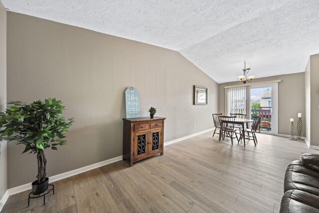 7603 Charlesway Dr Unit 87, Columbus, OH 43085 - living room with a chandelier, a textured ceiling, lofted ceiling, and light wood-style flooring