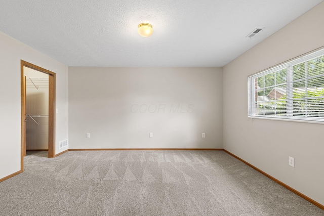 6858 Winrock Dr, New Albany, OH 43054 - unfurnished bedroom featuring carpet, a walk in closet, a closet, and a textured ceiling