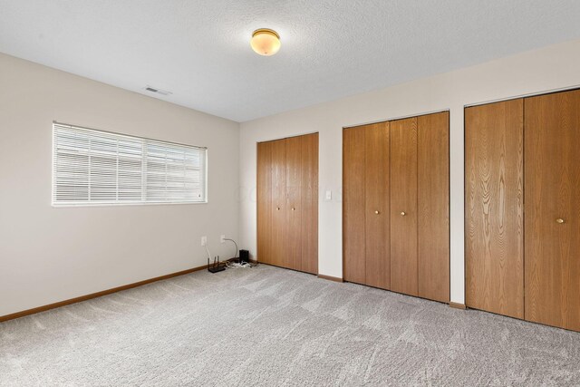 6858 Winrock Dr, New Albany, OH 43054 - unfurnished bedroom with two closets, light colored carpet, and a textured ceiling