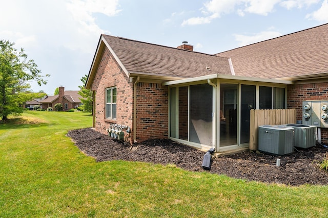 9427 Clermont Cir, Powell, OH 43065 - back of house featuring brick siding, a shingled roof, a chimney, and a sunroom
