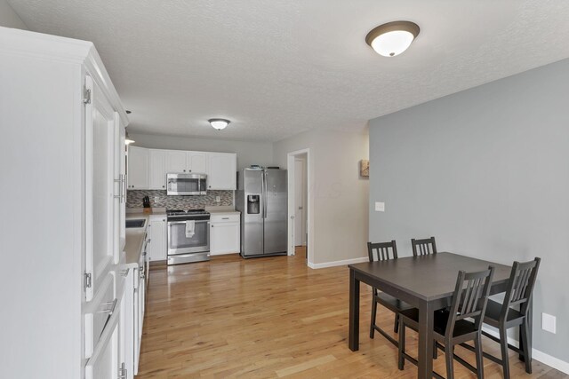5010 Nelson Dr, South Bloomfield, OH 43103 - kitchen featuring appliances with stainless steel finishes, light wood-style floors, white cabinets, tasteful backsplash, and a textured ceiling