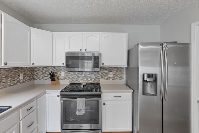 5010 Nelson Dr, South Bloomfield, OH 43103 - kitchen featuring appliances with stainless steel finishes, white cabinetry, a textured ceiling, decorative backsplash, and light countertops