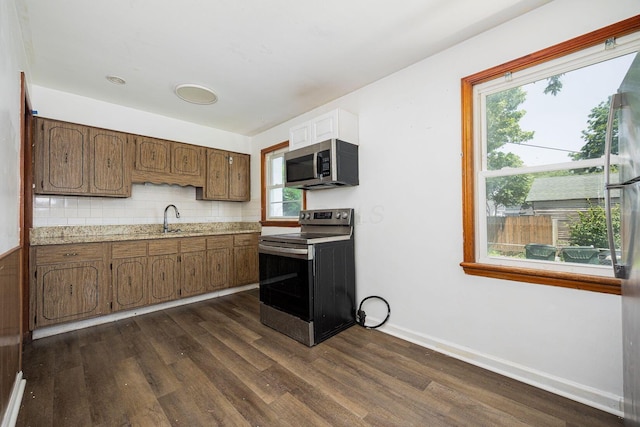 1900 S Champion Ave, Columbus, OH 43207 - kitchen featuring appliances with stainless steel finishes, dark wood finished floors, light countertops, decorative backsplash, and brown cabinets