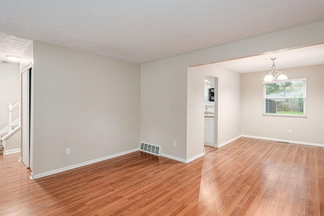 8800 Greenburg Dr, Powell, OH 43065 - unfurnished room with light wood-style floors, baseboards, a chandelier, and a textured ceiling