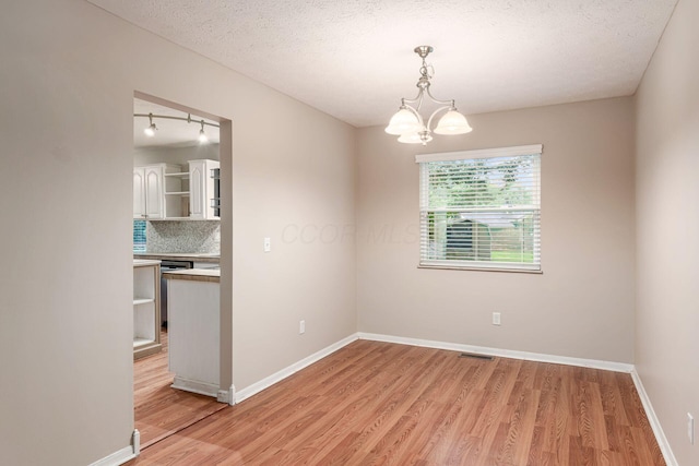 8800 Greenburg Dr, Powell, OH 43065 - spare room with light wood-type flooring, a chandelier, baseboards, and a textured ceiling
