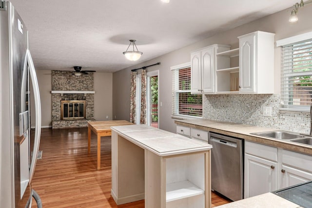 8800 Greenburg Dr, Powell, OH 43065 - kitchen featuring appliances with stainless steel finishes, open shelves, light wood finished floors, open floor plan, and a textured ceiling