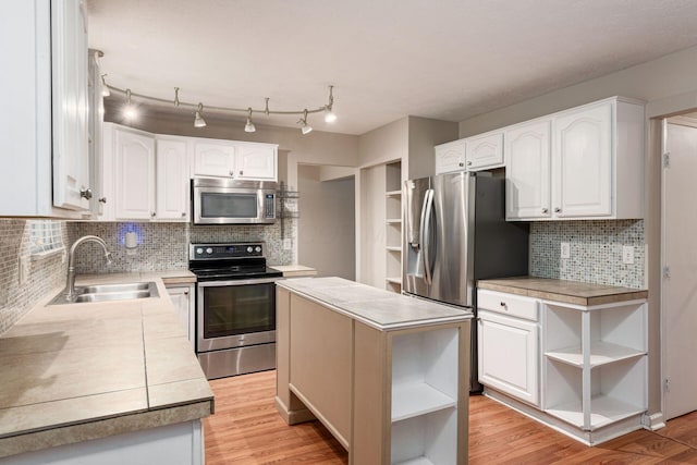 8800 Greenburg Dr, Powell, OH 43065 - kitchen with stainless steel appliances, open shelves, a sink, white cabinets, and light wood-type flooring