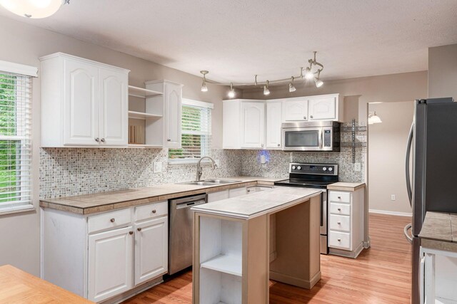 8800 Greenburg Dr, Powell, OH 43065 - kitchen featuring stainless steel appliances, open shelves, a sink, and white cabinets