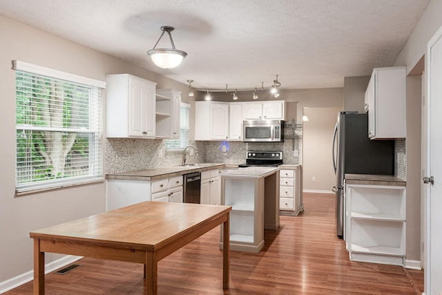8800 Greenburg Dr, Powell, OH 43065 - kitchen featuring appliances with stainless steel finishes, open shelves, white cabinetry, light wood-type flooring, and backsplash