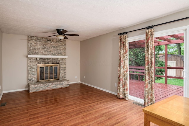 8800 Greenburg Dr, Powell, OH 43065 - unfurnished living room featuring wood finished floors, ceiling fan, a textured ceiling, baseboards, and a brick fireplace
