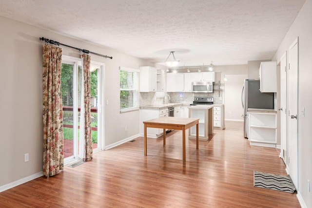 8800 Greenburg Dr, Powell, OH 43065 - kitchen featuring appliances with stainless steel finishes, open shelves, light wood-type flooring, a textured ceiling, and decorative backsplash