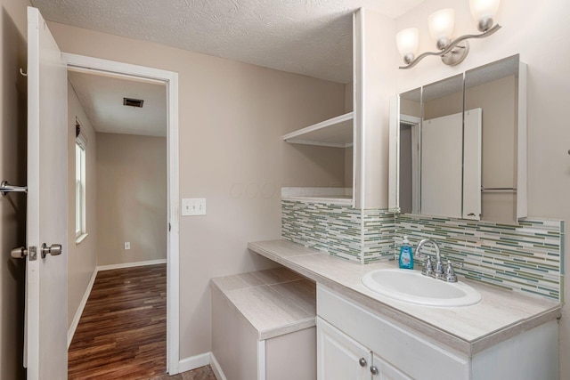 8800 Greenburg Dr, Powell, OH 43065 - bathroom with tasteful backsplash, wood finished floors, vanity, baseboards, and a textured ceiling