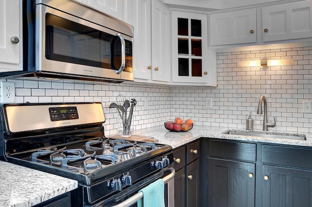 193 E Mithoff St Unit 193, Columbus, OH 43206 - kitchen with appliances with stainless steel finishes, tasteful backsplash, glass insert cabinets, white cabinetry, and light stone countertops