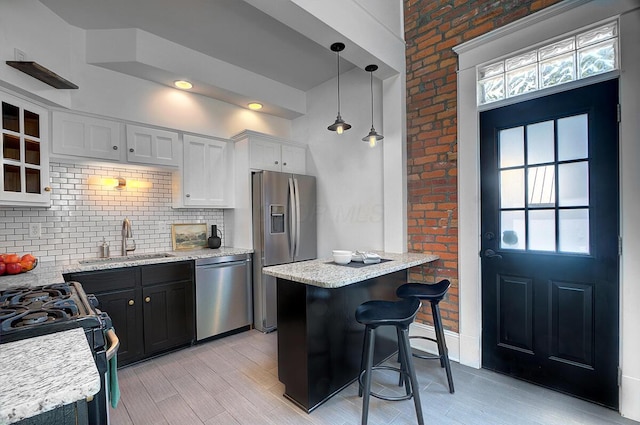 193 E Mithoff St Unit 193, Columbus, OH 43206 - kitchen with appliances with stainless steel finishes, decorative backsplash, a kitchen breakfast bar, light wood-style floors, and hanging light fixtures