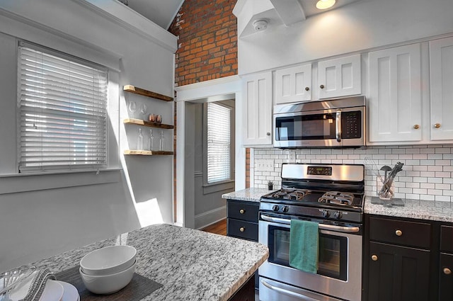 193 E Mithoff St Unit 193, Columbus, OH 43206 - kitchen with stainless steel appliances, tasteful backsplash, lofted ceiling, white cabinetry, and light stone countertops