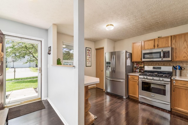 7524 Hemrich Dr, Canal Winchester, OH 43110 - kitchen with appliances with stainless steel finishes, light countertops, dark wood-style flooring, backsplash, and brown cabinets