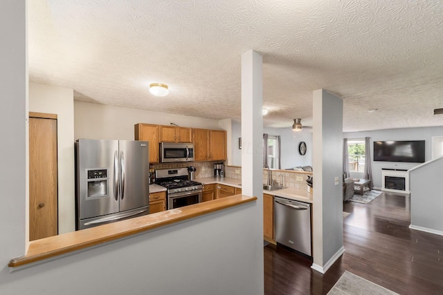 7524 Hemrich Dr, Canal Winchester, OH 43110 - kitchen featuring stainless steel appliances, a peninsula, a textured ceiling, dark wood-type flooring, and tasteful backsplash