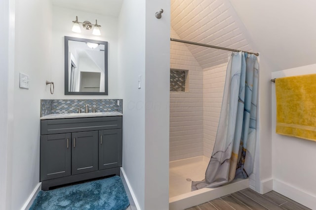 1167 Neil Ave, Columbus, OH 43201 - bathroom featuring vanity, a shower stall, wood finished floors, vaulted ceiling, and backsplash