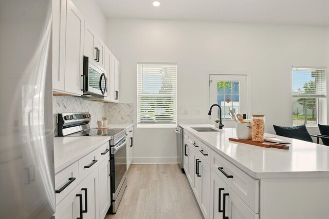 92 E Innis Ave, Columbus, OH 43207 - kitchen featuring appliances with stainless steel finishes, a peninsula, backsplash, light countertops, and white cabinets