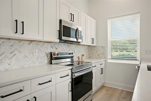 92 E Innis Ave, Columbus, OH 43207 - kitchen featuring stainless steel appliances, backsplash, light wood-type flooring, light countertops, and white cabinetry