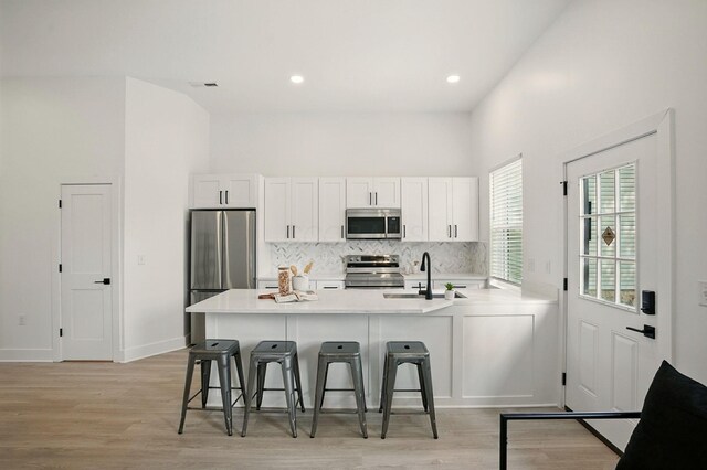 92 E Innis Ave, Columbus, OH 43207 - kitchen featuring appliances with stainless steel finishes, a peninsula, a breakfast bar, decorative backsplash, and white cabinets