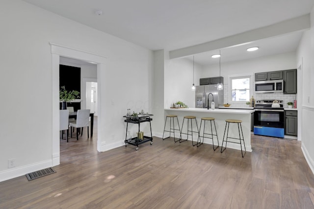 638 E 6th Ave, Lancaster, OH 43130 - kitchen with appliances with stainless steel finishes, a breakfast bar, wood finished floors, and a peninsula
