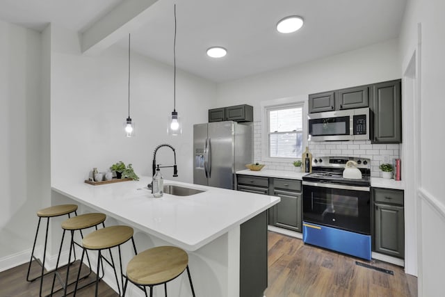 638 E 6th Ave, Lancaster, OH 43130 - kitchen with stainless steel appliances, gray cabinets, a kitchen breakfast bar, backsplash, and dark wood-style flooring