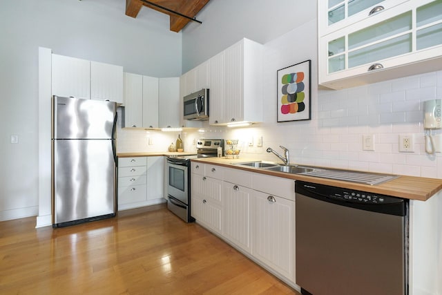 150 E Main St Unit 405, Columbus, OH 43215 - kitchen featuring stainless steel appliances, backsplash, light wood-style flooring, a towering ceiling, and white cabinets