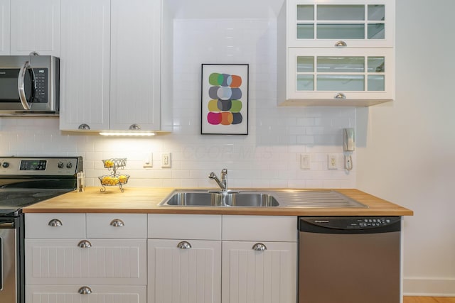 150 E Main St Unit 405, Columbus, OH 43215 - kitchen with appliances with stainless steel finishes, wooden counters, backsplash, and glass insert cabinets