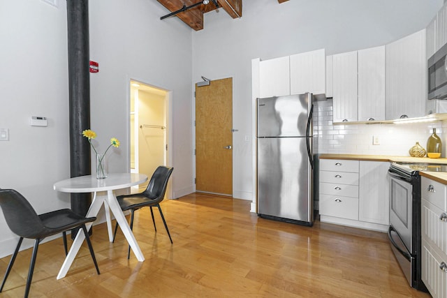 150 E Main St Unit 405, Columbus, OH 43215 - kitchen featuring stainless steel appliances, a high ceiling, backsplash, light wood-type flooring, and white cabinets