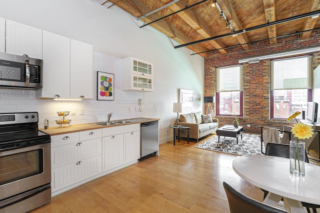 150 E Main St Unit 405, Columbus, OH 43215 - kitchen featuring stainless steel appliances, a wooden ceiling with exposed beams, track lighting, butcher block counters, and brick wall
