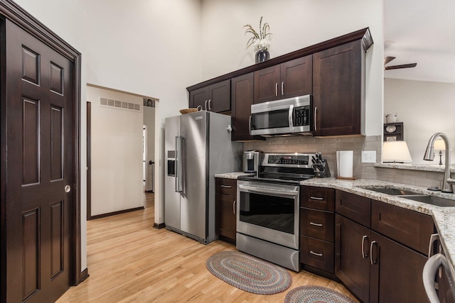 2461 Abbey Knoll Dr, Lewis Center, OH 43035 - kitchen with stainless steel appliances, light wood-type flooring, dark brown cabinets, decorative backsplash, and a ceiling fan