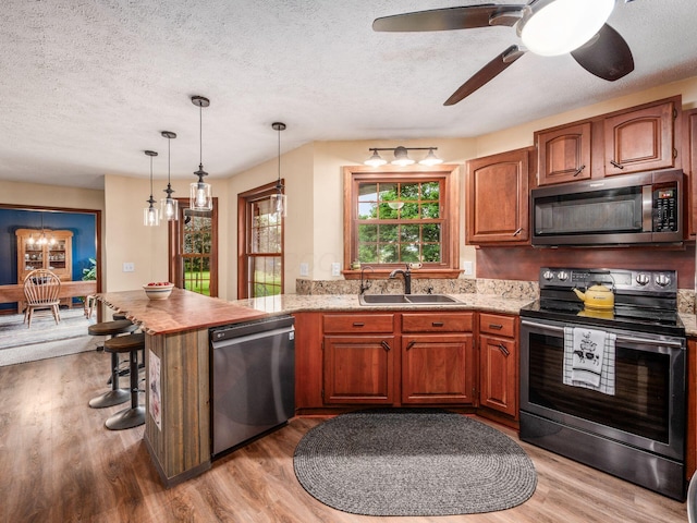 8120 Morgan Rd, West Jefferson, OH 43162 - kitchen with stainless steel appliances, a peninsula, a textured ceiling, light wood finished floors, and a chandelier