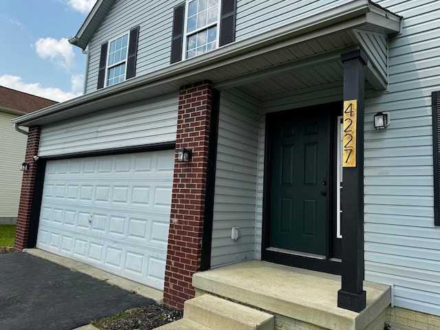 4227 Sestos Dr, Columbus, OH 43207 - property entrance with an attached garage, asphalt driveway, and brick siding