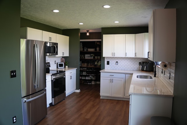 4227 Sestos Dr, Columbus, OH 43207 - kitchen with stainless steel appliances, a textured ceiling, tasteful backsplash, dark wood-style floors, and white cabinetry