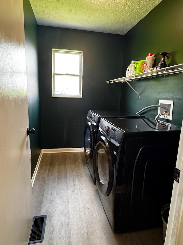 4227 Sestos Dr, Columbus, OH 43207 - laundry area featuring washer and clothes dryer, wood finished floors, and a textured ceiling
