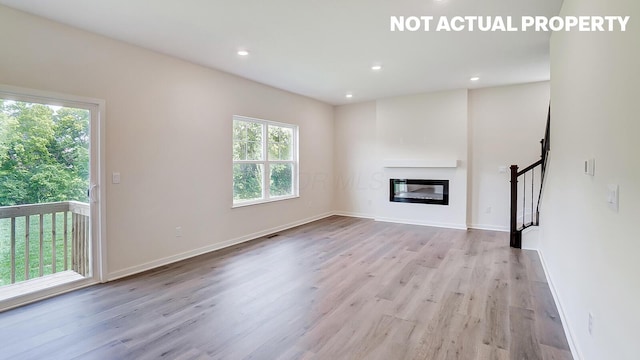 786 Sunny Vale Dr, Delaware, OH 43015 - unfurnished living room with wood finished floors, stairway, a glass covered fireplace, recessed lighting, and baseboards