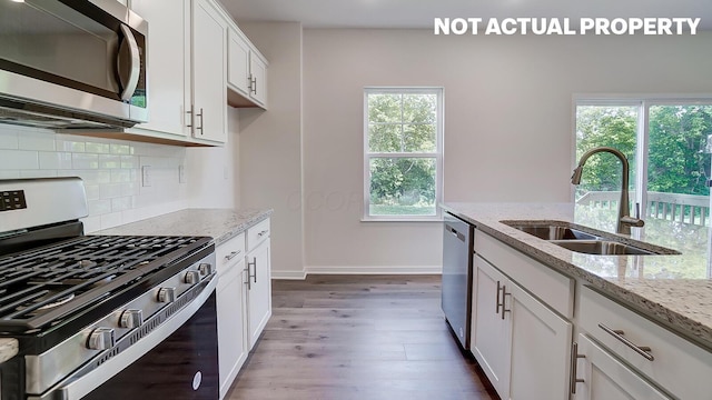 786 Sunny Vale Dr, Delaware, OH 43015 - kitchen with appliances with stainless steel finishes, a sink, wood finished floors, tasteful backsplash, and light stone countertops