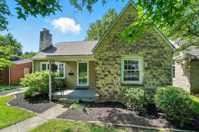 33 W Dominion Blvd, Columbus, OH 43214 - tudor home with stone siding, a chimney, and a shingled roof