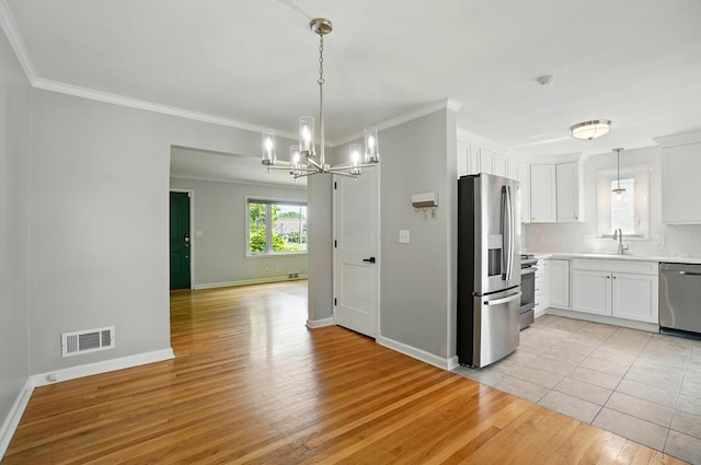 33 W Dominion Blvd, Columbus, OH 43214 - kitchen featuring stainless steel appliances, a chandelier, light countertops, white cabinetry, and ornamental molding