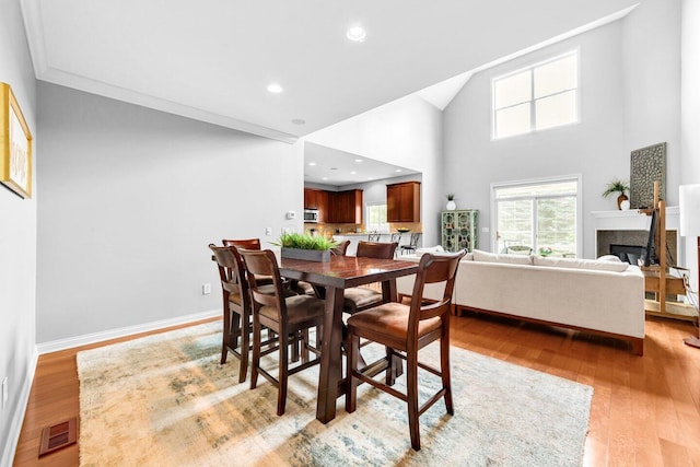 4724 Trademark Trl, Hilliard, OH 43026 - dining room with a glass covered fireplace, light wood-style flooring, ornamental molding, high vaulted ceiling, and baseboards